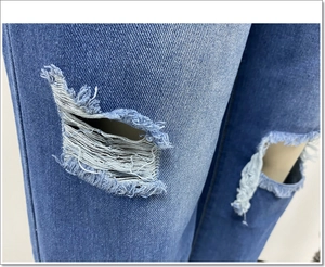 Detailopname van de knie-openingen en witte rafelige vezels op de blauwe jeans