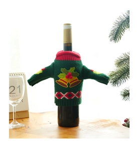 Close-up of a green knitted Christmas wine bottle cover with bell and berry details
