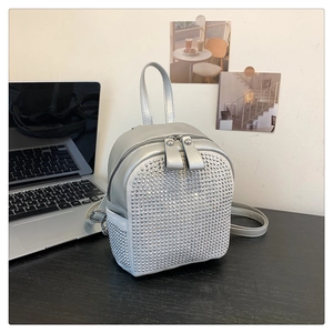 Detailed view of a mini silver backpack with rhinestone embellishments on a desk