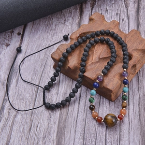 Détail de perles en lave noire 6mm avec sept gemmes chakra et pendentif en oeil de tigre