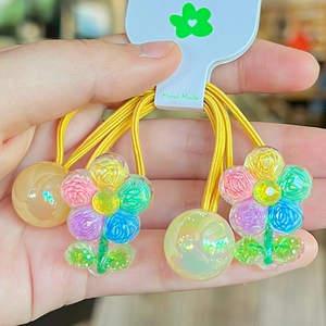 Dettaglio di ciondoli a fiore in resina colorata su elastici per capelli gialli