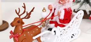 Electric Santa Claus toy on a white sleigh pulled by a brown reindeer on a table
