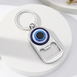 Vue détaillée du porte-clés décapsuleur en métal argenté avec œil bleu sur socle blanc