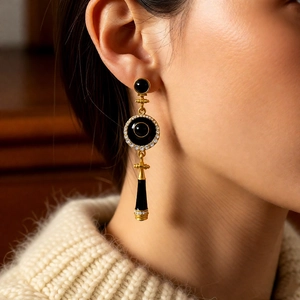 Macro shot of vintage round drop earrings with black enamel and gold accents on a model