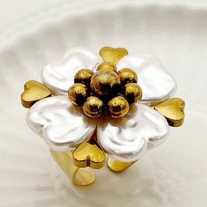 Macro view of golden flower ring with white coral petals and sparkling zircon detail