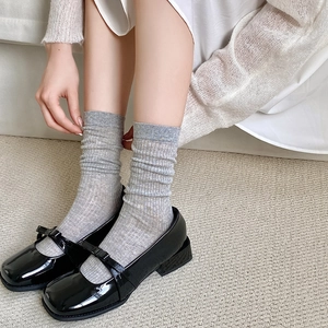 Close-up of light gray ribbed knit socks paired with black Mary Jane shoes for daily wear