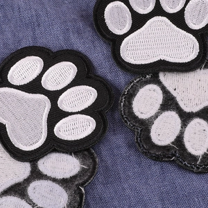 Black and white paw print embroidery patches scattered on blue denim fabric background
