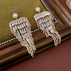 Close-up of vintage gold tassel earrings with clear cubic zirconia on dark velvet background