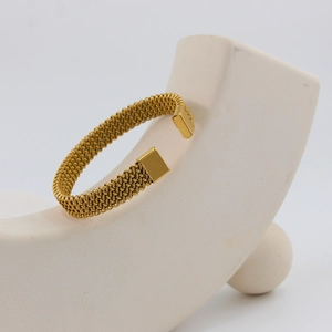 Detail of 18K gold plated mesh braided open cuff bracelet on white display stand