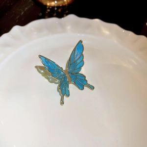 Macro detail of blue butterfly clip with golden edges and shimmering enamel texture
