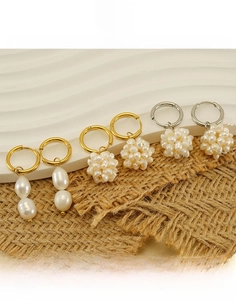 Detail of 18k gold plated titanium steel earrings with natural pearls on white waves