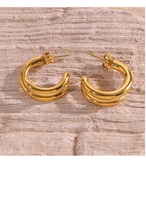 Detailed view of double-layer golden hoop earrings on a textured stone surface