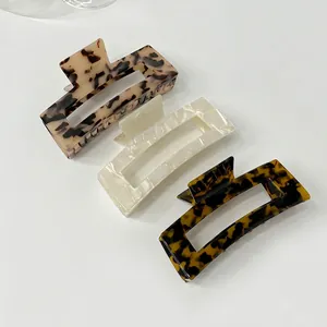 Three rectangular acetate hair claws in tortoiseshell and marble patterns on white background