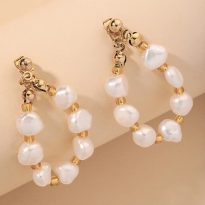 Macro detail of French style hoop earrings with baroque pearls and gold accents