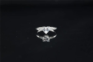 Detail of silver heart-shaped moissanite ring with side accent diamonds on black background