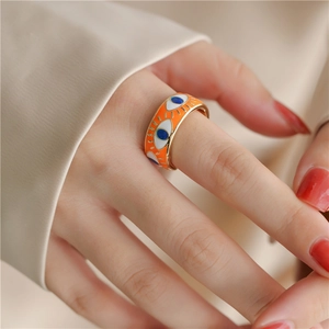 Detail of wide 18K gold plated ring featuring orange enamel and Evil Eye design