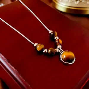 Collier avec pendentif en œil de tigre et chaîne serpent sur un coffret en bois chic