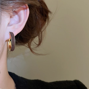 Close-up of retro C-shaped earrings with brown velvet texture and gold metal inner lining