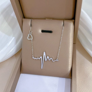Macro shot of silver heartbeat pendant and hollow heart detail on titanium steel necklace