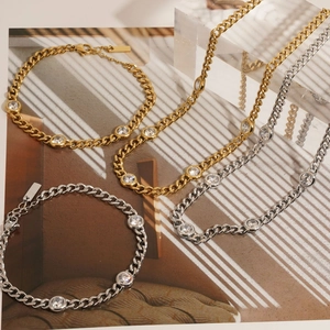 Gold and silver Cuban chain bracelets set with round cubic zirconia on textured background