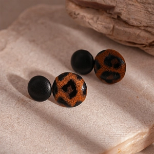 Detail shot of leopard print and black fabric earrings on natural stone surface