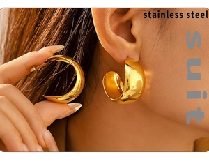 Detail of model wearing large gold PVD plated C-shaped stainless steel earrings
