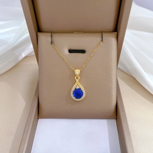Luxurious gold teardrop necklace featuring a blue gemstone with white crystal halo