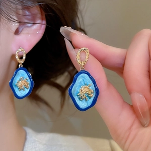 Gros plan de boucles d'oreilles fleurs ovales vintage avec dégradé bleu et doré