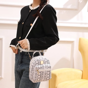 Close-up of a white snakeskin pattern mini backpack with gold hardware worn by a model
