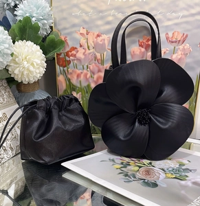 Detailed macro view of black petal flower handbag and matching drawstring storage pouch