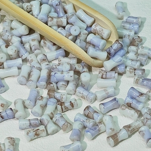 Vue macro de perles en céramique 6x12mm forme bambou avec texture marbrée et trou central