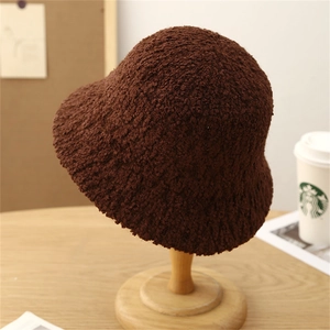 Detailed texture of dark brown faux shearling knit bucket hat on a wooden stand