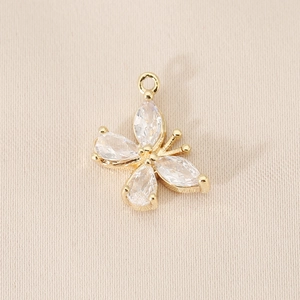 Macro detail of 18K gold-plated butterfly charm with marquise cubic zirconia on fabric