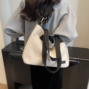 Minimalist beige canvas tote bag with black wide straps shown on a model for daily commute