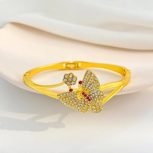 Retro-Armreif Gold mit Schmetterlingen und rosa-weißen Strasssteinen auf beigem Grund