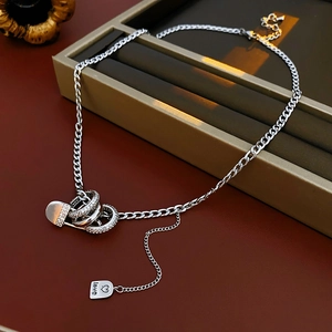 Detail of silver paperclip chain necklace with zircon rings and engraved LOVE heart tag