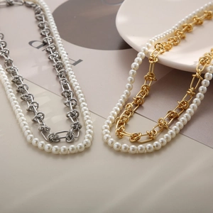 Détail d'un collier double épaisseur en acier inoxydable avec nœuds et perles dorés et argentés