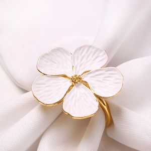 Elegant white painted flower napkin ring with gold trim on soft white fabric background