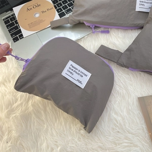 Close-up of gray waterproof nylon storage bag with purple zipper and woven label detail