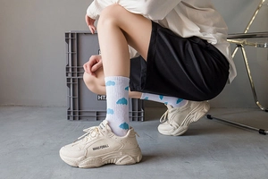 Close-up of white platform sneakers with blue cloud pattern socks in a studio setting