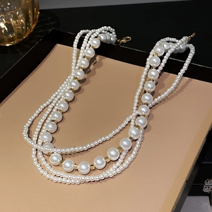 Detail of multilayer pearl necklace with gold square beads on elegant display tray