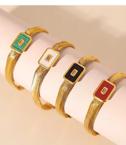 Detail of PVD electroplated gold bracelets featuring colorful square glass stones