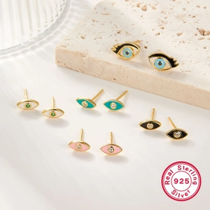 Detail of colorful enamel evil eye studs in 925 sterling silver on stone backdrop