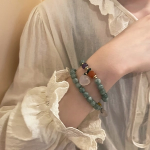 Close-up of dual-layer natural stone beaded bracelet with pink drop pendant on a wrist