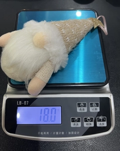 Close-up of a handmade knitted gnome ornament with a gold star being weighed at 18.0g