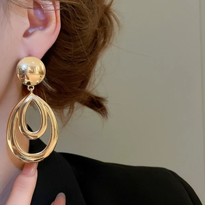 Vue rapprochée de boucles d'oreilles dorées en forme de double goutte évidée sur un mannequin
