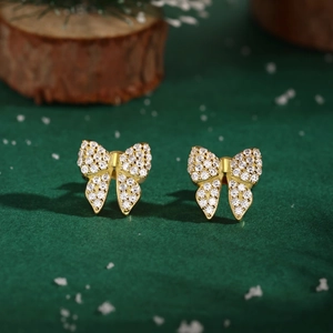 Close-up of golden bow-shaped stud earrings with sparkling pave-set cubic zirconia