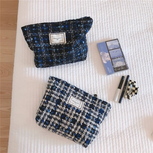 Detailed view of tweed makeup bags in blue weaves with Time to Party woven labels