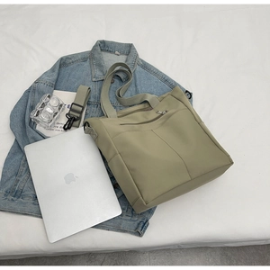 Detailed view of light green canvas tote bag with front zipper pocket and adjustable strap