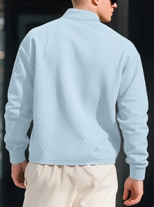 Macro shot of light blue polo shirt featuring intricate geometric jacquard fabric texture